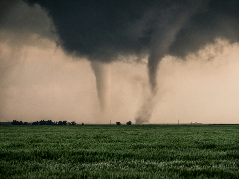 Two tornadoes near each other on an open plain.